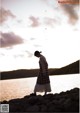 A woman standing on a rock by the water.