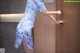 A woman in a blue and white dress is opening a door.