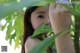 A woman holding a green leaf in front of her face.