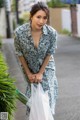 A woman in a blue dress holding a plastic bag.