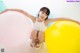 A young girl sitting on the floor with a bunch of balloons.