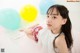 A young girl laying on the floor with colorful balloons.