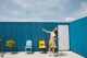 A woman in a bikini holding a hose in front of a blue wall.