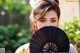 A woman in a kimono holding a black fan.