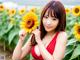 A woman in a red dress holding a sunflower in a field.