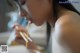 A woman eating noodles with chopsticks in her mouth.