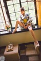 A woman sitting on a window sill in a room.